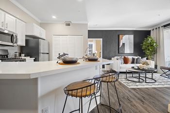 an open kitchen and living room with a white counter and stools
